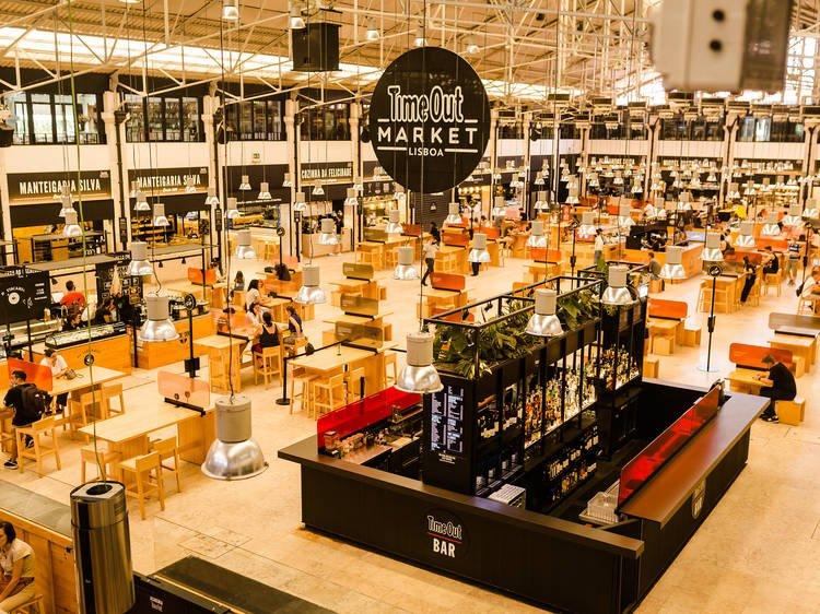 Vibrant interior view of Time Out Market in Lisbon with bustling crowds and food stalls.