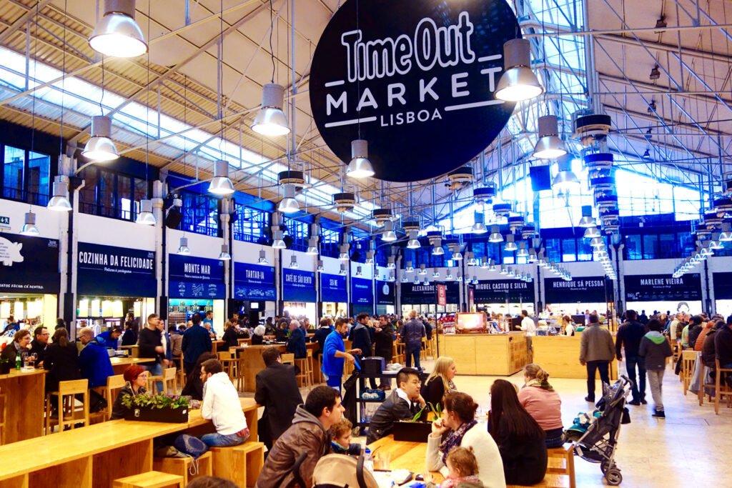 Vibrant interior view of Time Out Market in Lisbon with bustling crowds and food stalls.