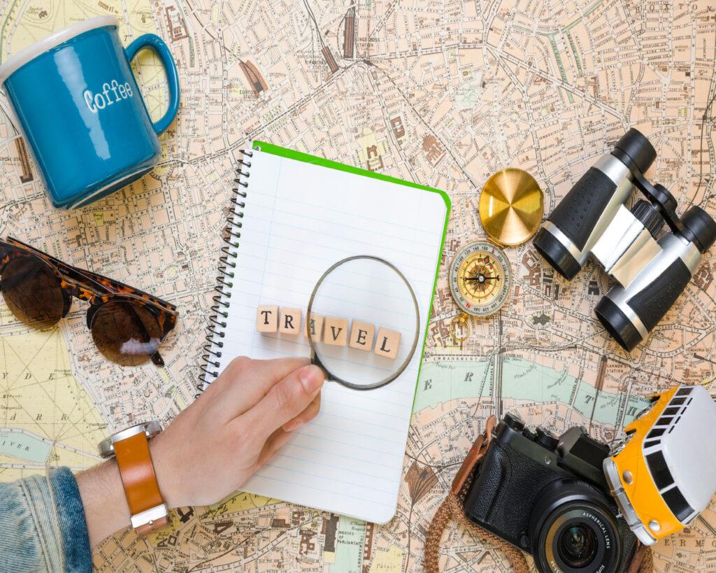 A traveler reading a travel guide while planning their trip, with a suitcase and travel essentials in the background.